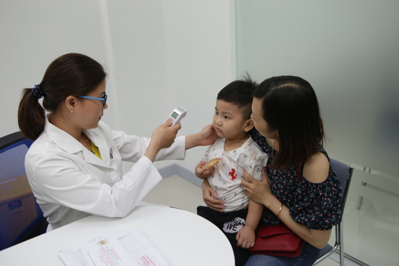 đo nhiệt độ trẻ trước khi tiêm vắc xin