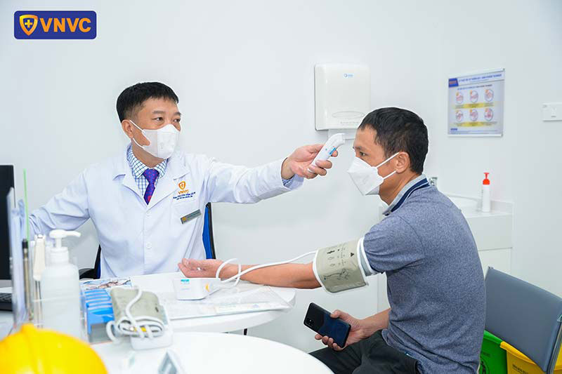bác sĩ đo thân nhiệt cho người tiêm