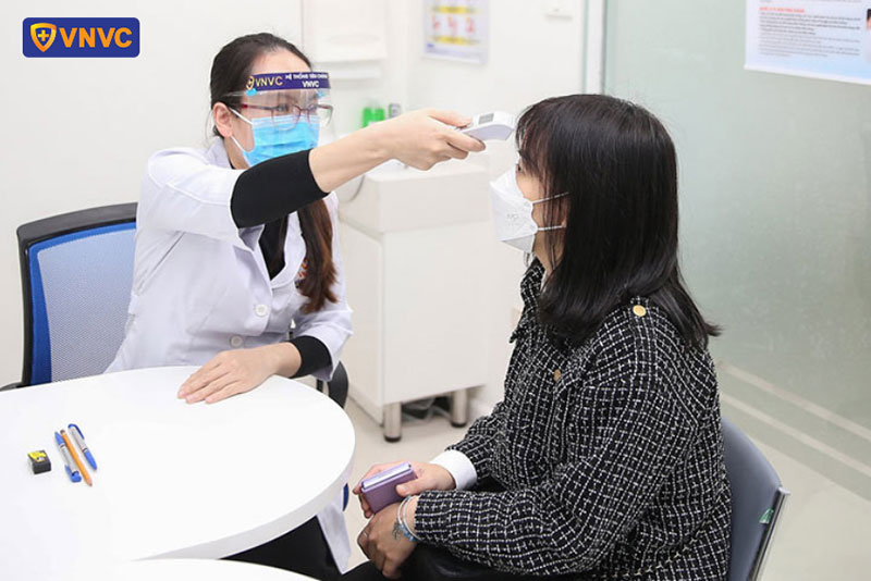 bác sĩ đo thân nhiệt cho người tiêm