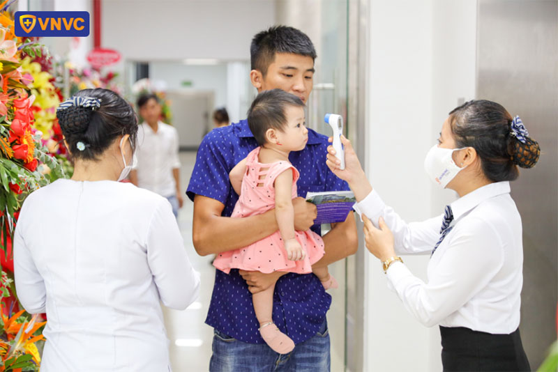 nhân viên vnvc dĩ an đo thân nhiệt cho khách hàng