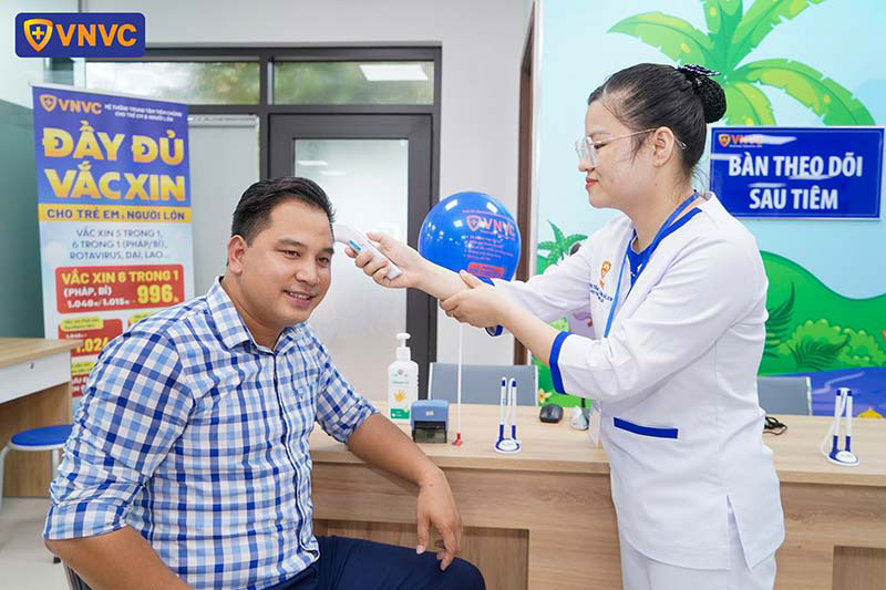 nhân viên vnvc đo thân nhiệt cho khách hàng