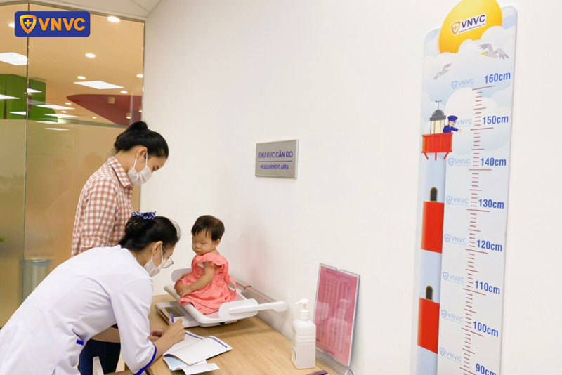 điều dưỡng tiến hành cân bé