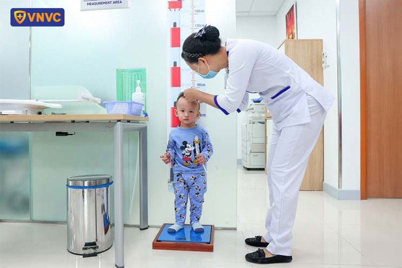 điều dưỡng viên đo chiều cao cho bé