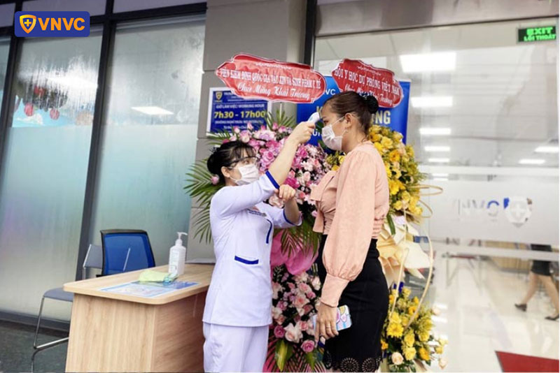 nhân viên vnvc cà mau đo thân nhiệt cho khách hàng
