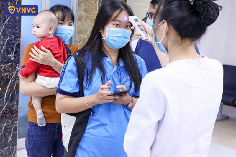 nhân viên vnvc long thành đo thân nhiệt cho khách hàng