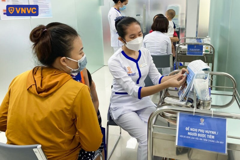 điều dưỡng đối chiếu thông tin vắc xin cho phụ huynh