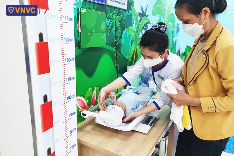 điều dưỡng hỗ trợ đo cân nặng cho bé