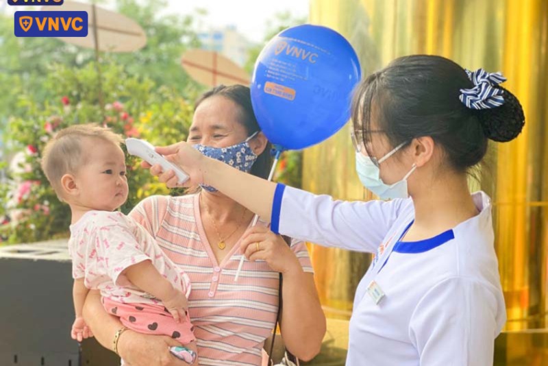 nhân viên vnvc đồng hới đo nhiệt độ cho bé