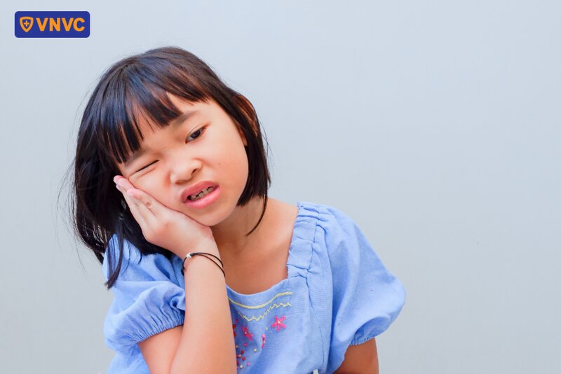 bé ôm vùng quai hàm bị đau