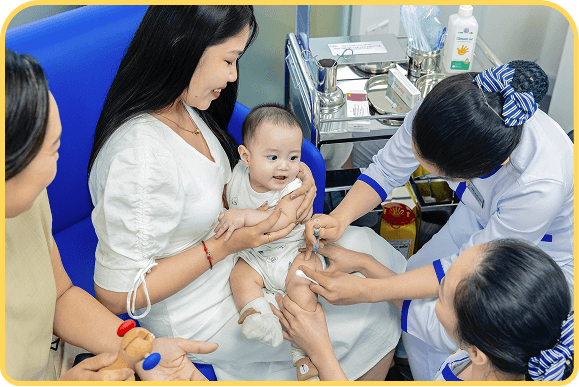 mẹ bế bé tiêm vắc xin