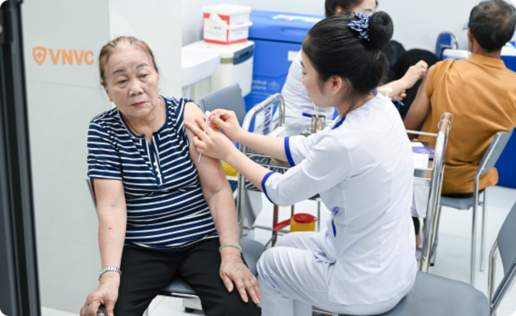 phụ nữ lớn tuổi đang được nhân viên tiêm phòng