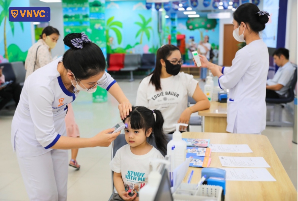 đo nhiệt độ trẻ trước khi tiêm phòng