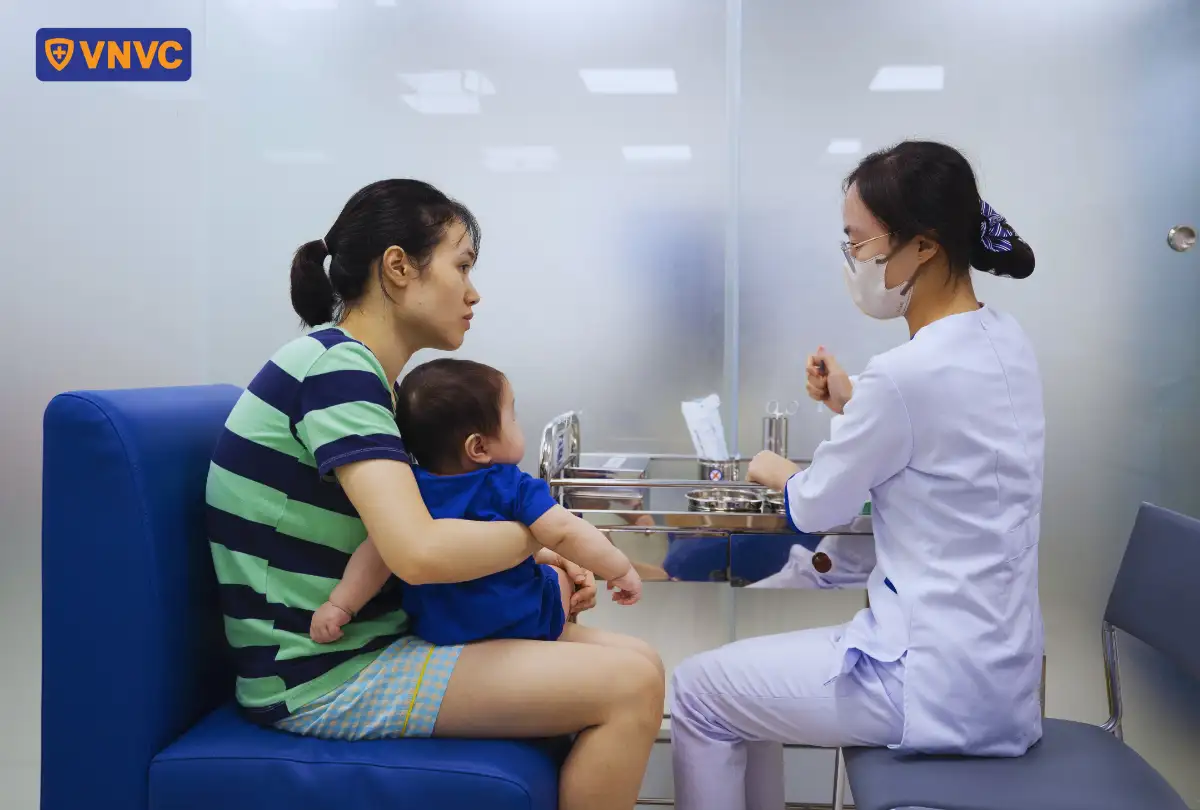 mẹ ẵm con tiêm vắc xin