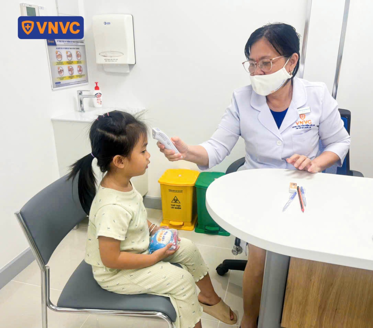 bác sĩ đo nhiệt độ cho bé gái