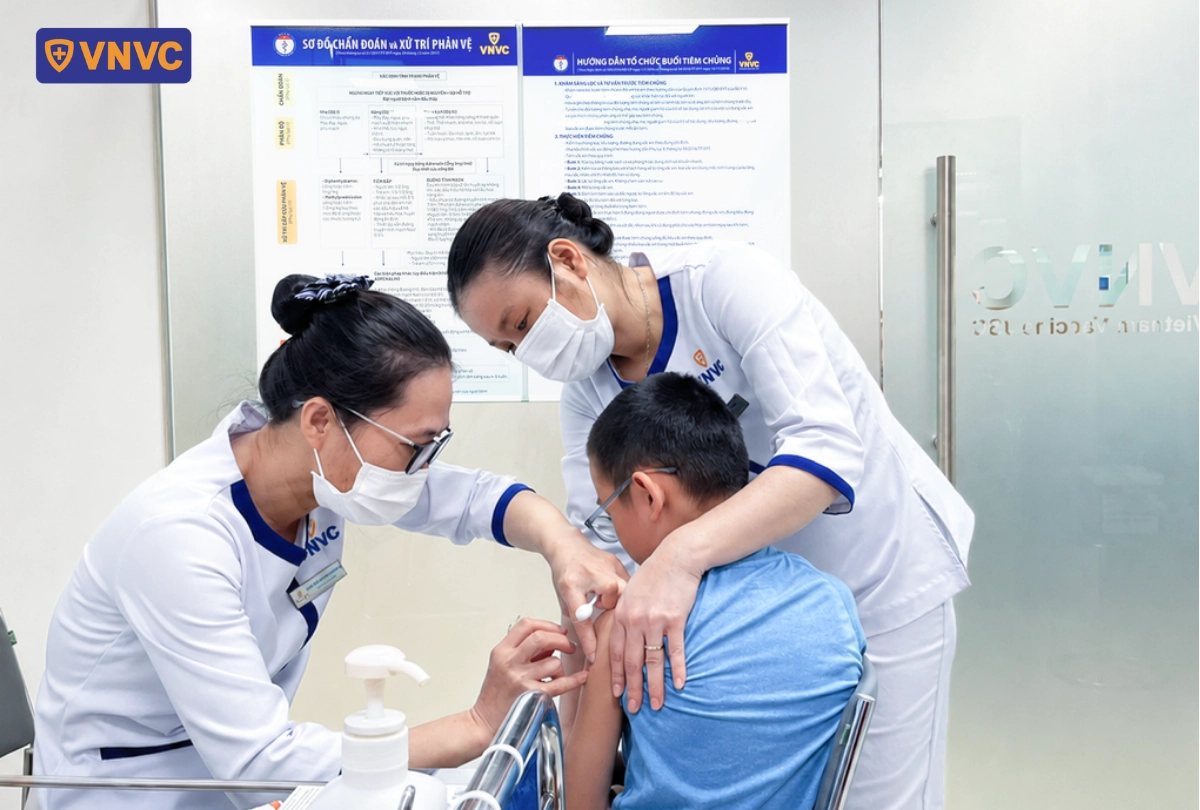 bé được điều dưỡng tiêm vắc xin