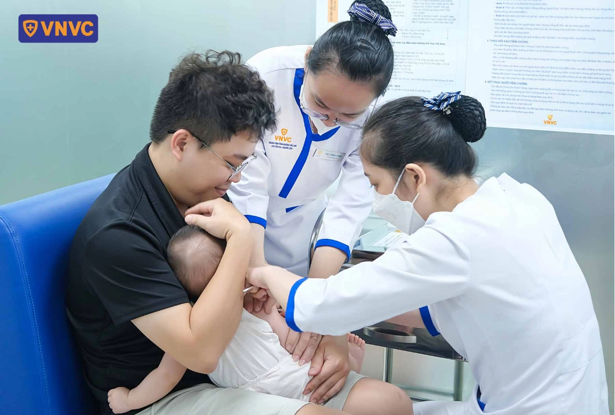 bố bế con tiêm vắc xin