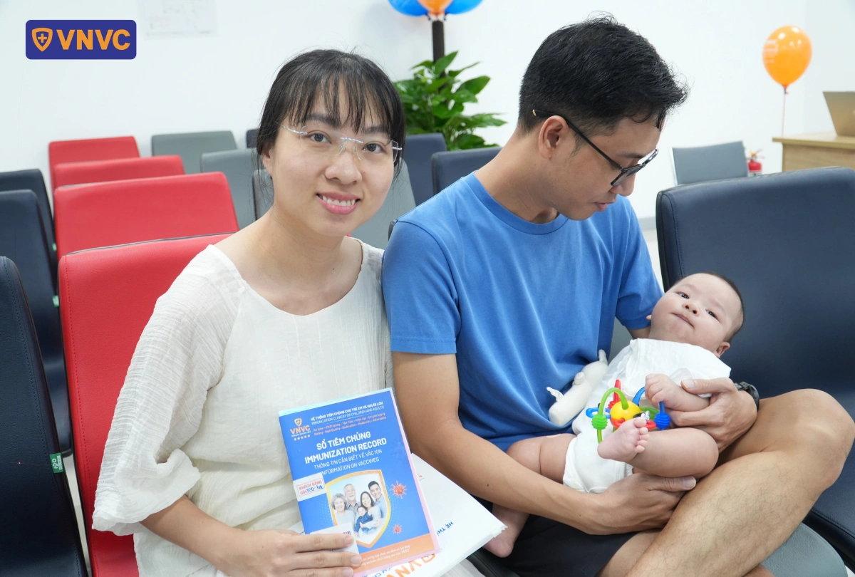 mẹ và bố ẵm con đi tiêm ngừa