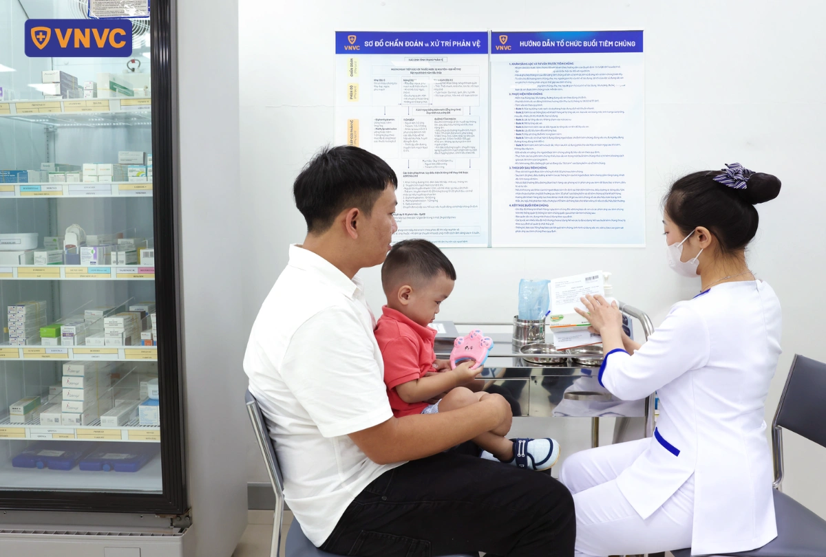 bố ẵm con đi tiêm vắc xin
