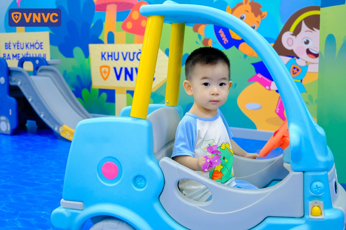 em bé trai ngồi trong xe mô hình