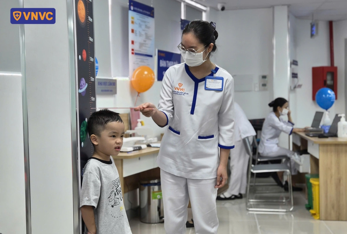 bé đo chiều cao trước khi tiêm